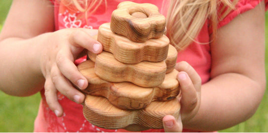  young girl joyfully holds a colorful wooden toy stack, showcasing her playful spirit and creativity.
